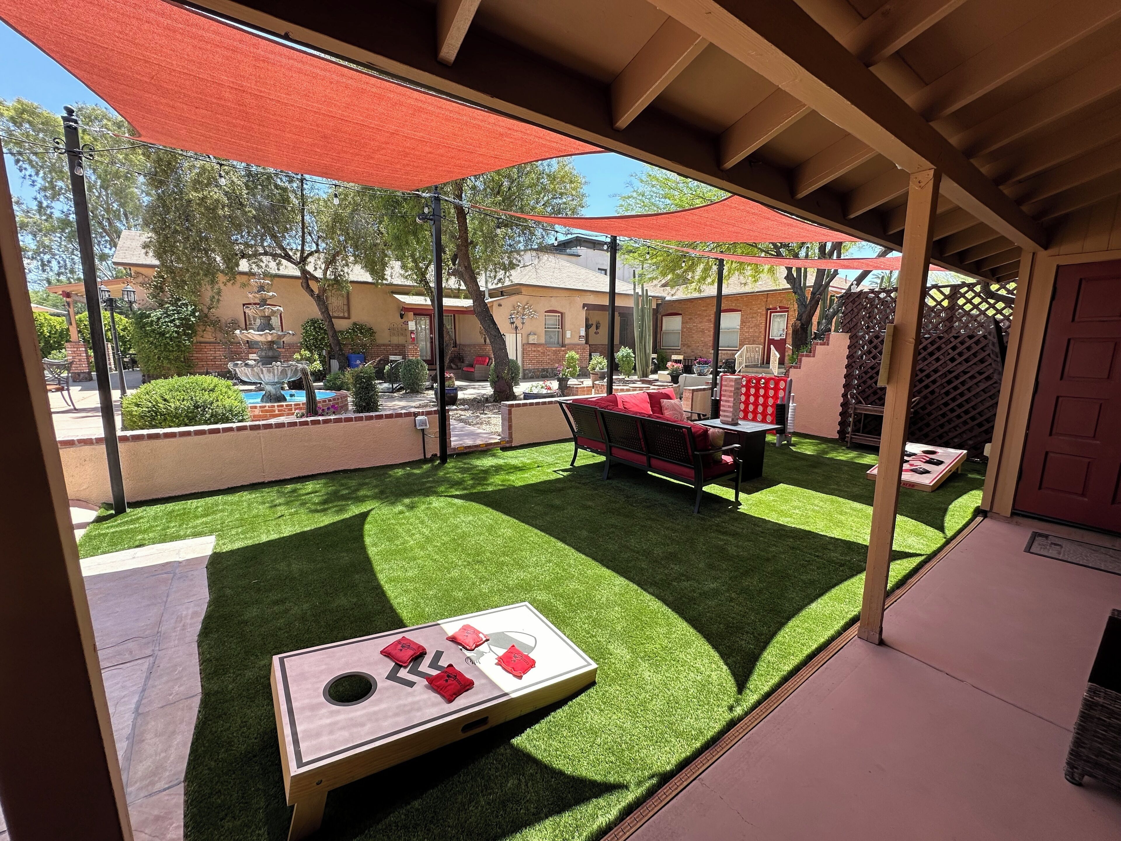 A covered patio area with artificial grass, a pool table, and outdoor furniture.
