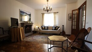 A living room with a fireplace, sofa, and a table. - Comfortable house with magnificent garden (Ponta Delgada)