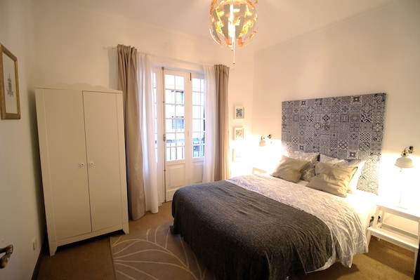 Une chambre à coucher comprenant un lit, une armoire, une porte et une tête de lit à motifs.