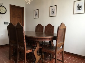 Une salle à manger avec une table et des chaises en bois, une horloge au mur et des tableaux encadrés.