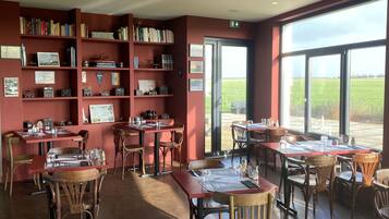 A restaurant with red walls, wooden furniture, and large windows offering a view of the outdoors.