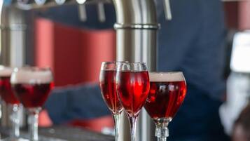 Un bar con grifo y vasos de bebida roja.