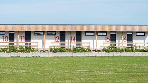 A row of numbered rooms with a simple, modern design, each with a bench outside. - l'Aérodrome de la Baie de Somme (Buigny-Saint-Maclou)