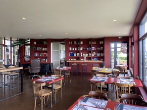 Eine Bibliothek mit Bücherregalen, Tischen, Stühlen und einem großen Fenster.