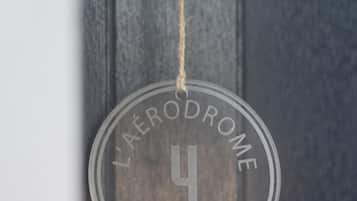 En rund skylt med texten ”L’AERODROME Hotel – Restaurant” hänger på en dörr.