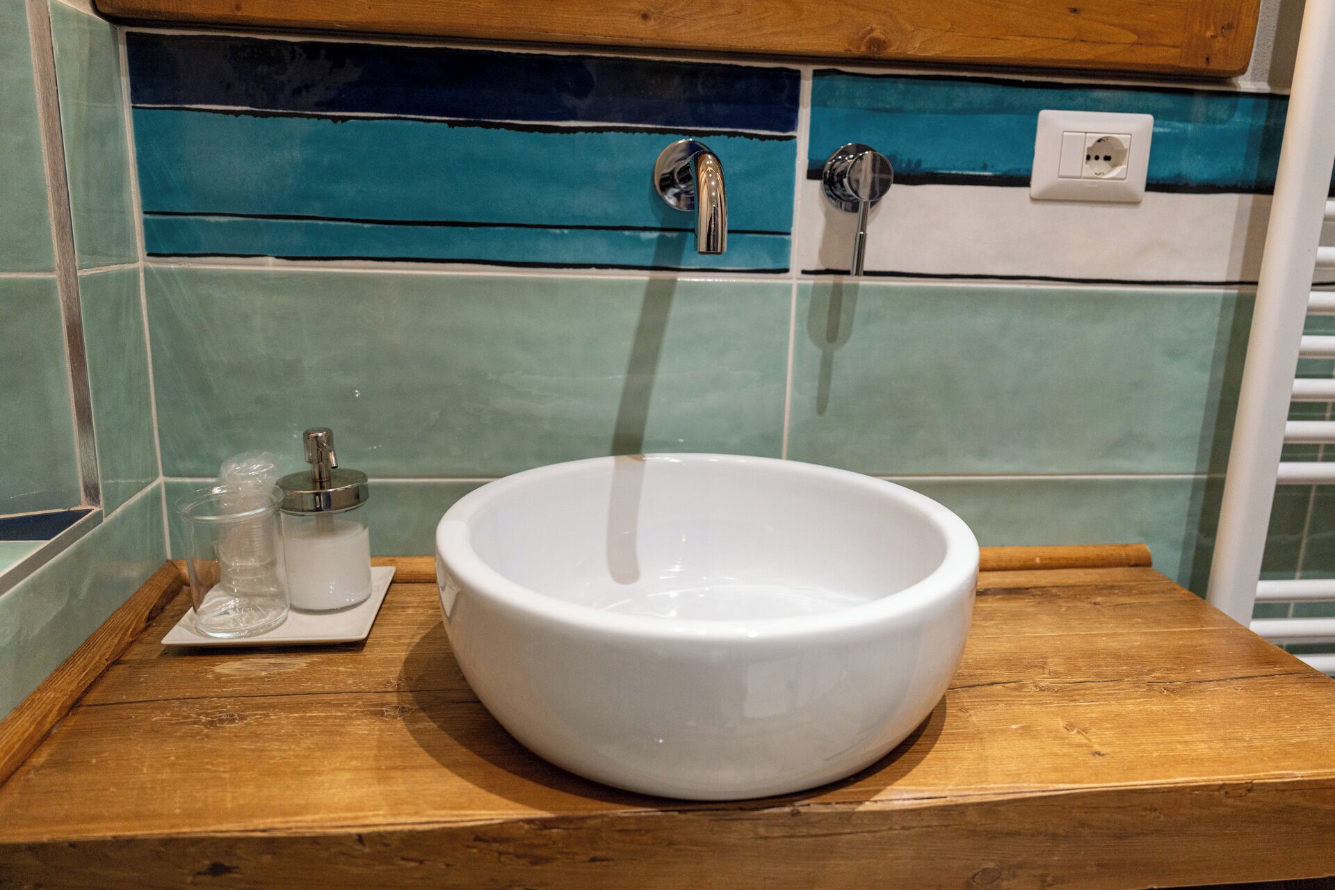 Un lavandino in ceramica bianca su un piano di lavoro in legno, con un pannello di legno sopra.