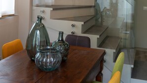 A modern dining area with a wooden table, glass vases, and a staircase with glass railings. - L' Eroico (Gaiole in Chianti)