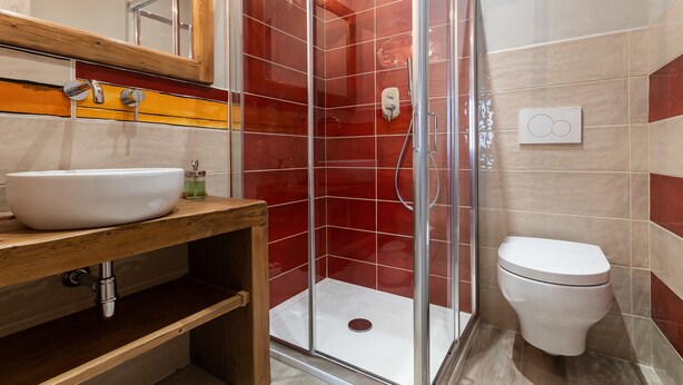 A bathroom with a white sink, wooden vanity, a glass-enclosed shower, and a white toilet. - L' Eroico (Gaiole in Chianti)