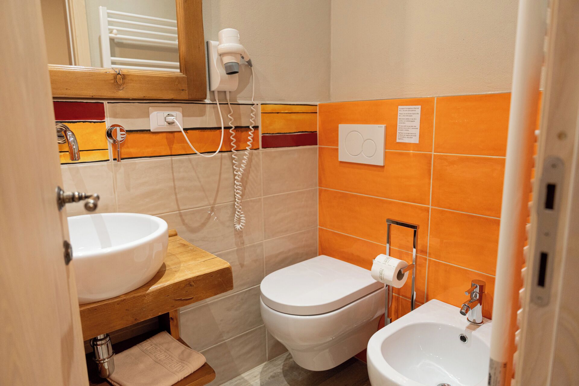 A bathroom with a sink, toilet, and bidet, a hairdryer, and a towel rack.