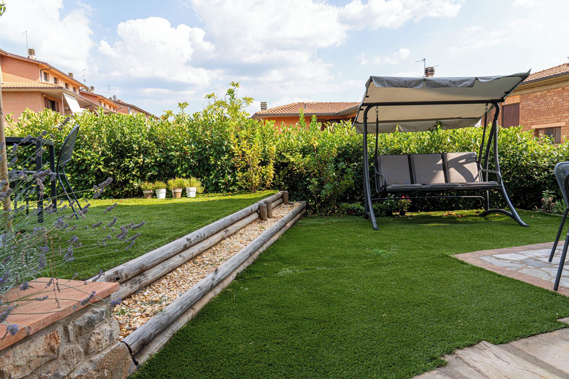 Un jardin bien entretenu, agrémenté d’une balançoire, d’un banc en bois et d’une pergola.