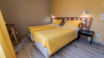 A room with two beds, wooden headboard, bedside tables, and a lamp.