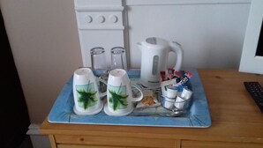 A kitchen counter with a coffee maker, salt and pepper shakers, a kettle, and a remote control. - Camillia Guest House (Aberdeen)