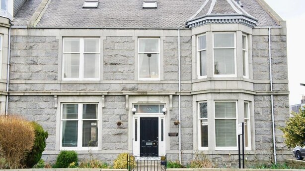 A stone building with a black front door, multiple windows, and a small garden area in front. - Camillia Guest House (Aberdeen)