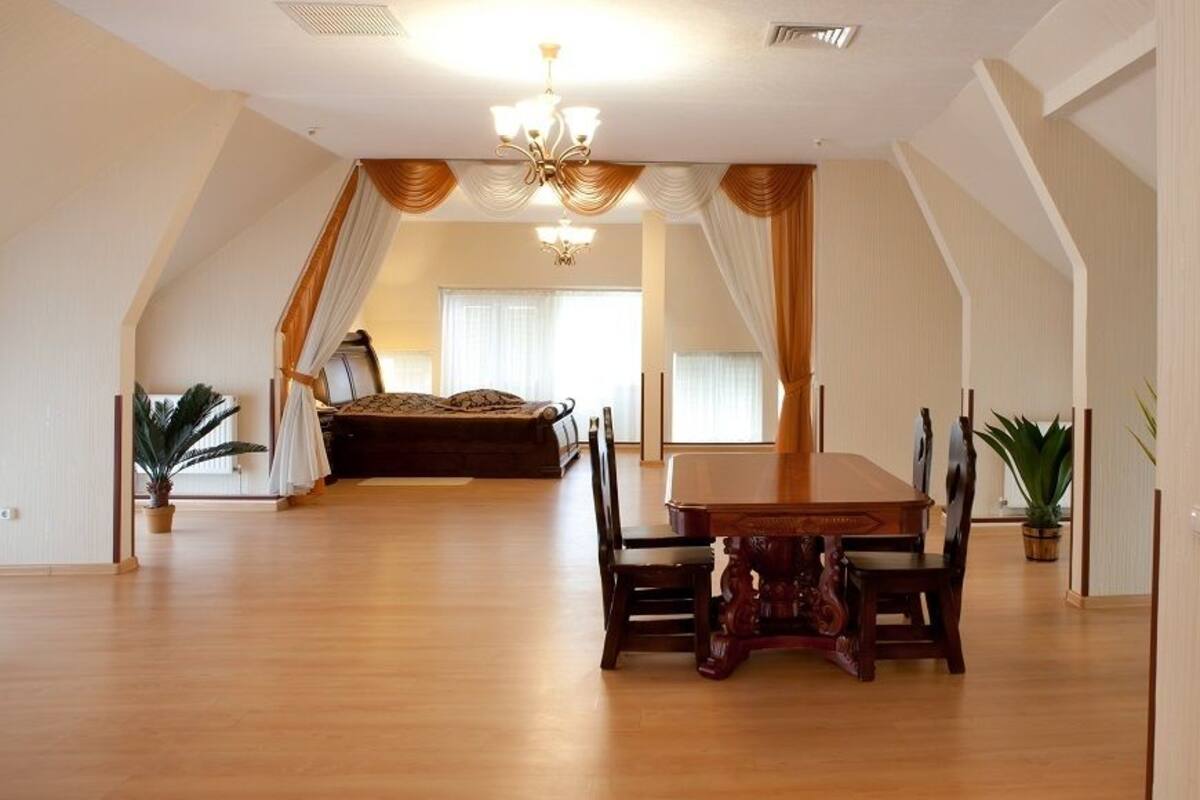 Una habitación amplia con una mesa de comedor grande, una cama y un candelabro.