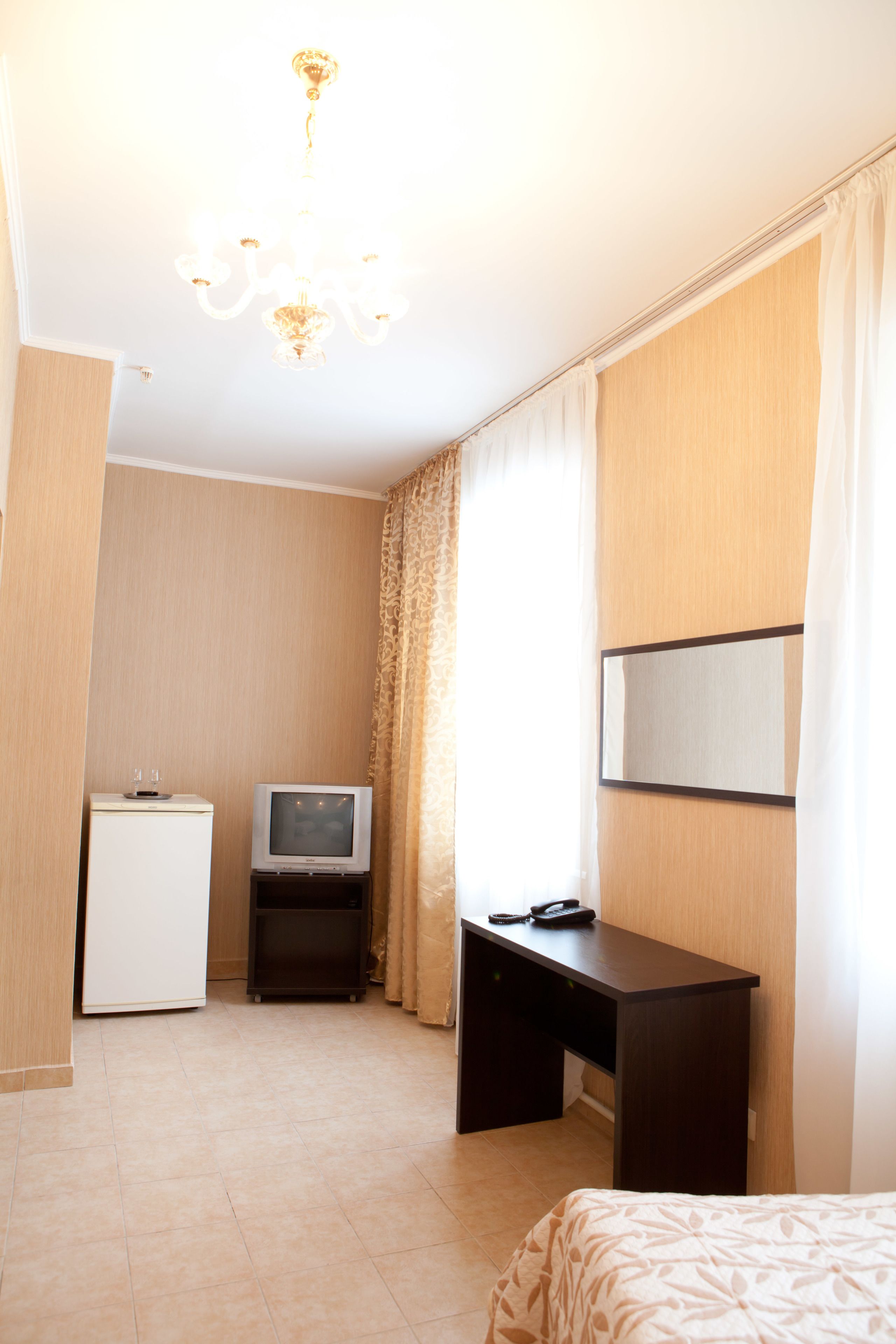 Una habitación de hotel con cama, escritorio, televisión y minibar.