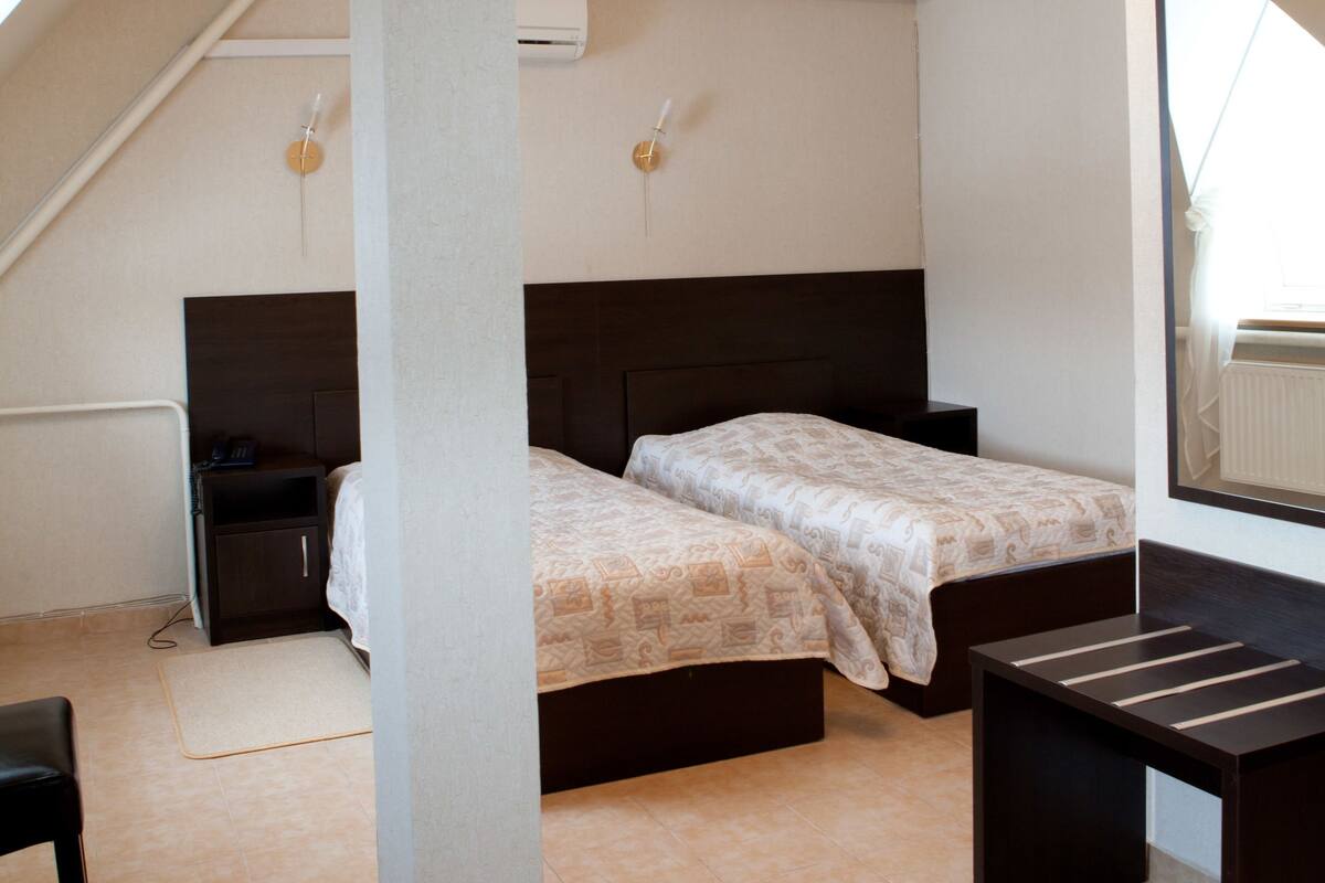 Un dormitorio con dos camas, un escritorio, una silla y un espejo grande.
