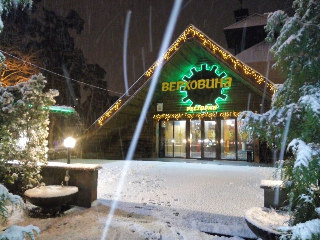 A building with a green sign reading "BERKHOBUHA" and "RETTORAN" at night.