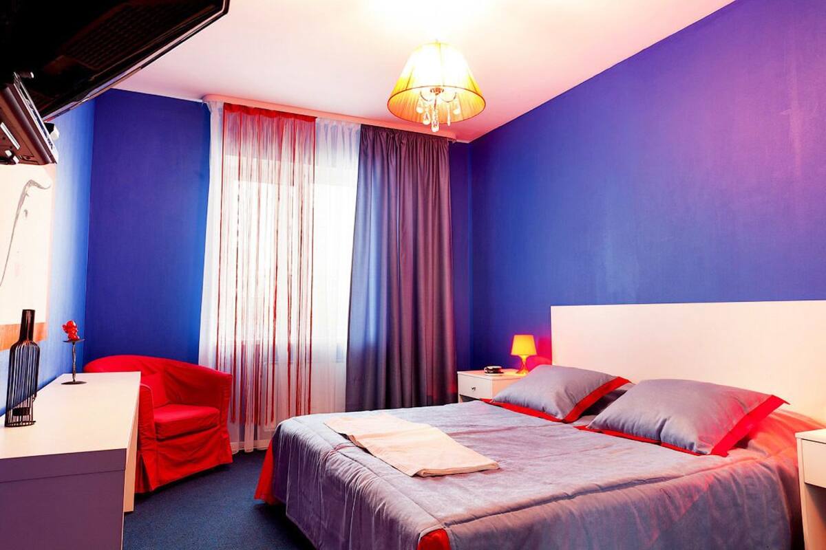Ein Hotelzimmer mit Bett, Schreibtisch, Stuhl, Nachttisch und Lampe.