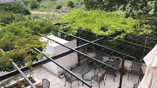 Une terrasse sur le toit dotée d’un toit en verre, d’un espace salon extérieur et d’un jardin.