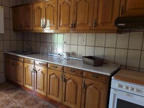 A kitchen with wooden cabinets, a white countertop, and a stove.
