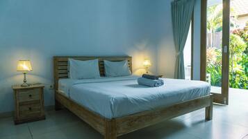 Un dormitorio con una cama de madera, dos mesitas de noche con lámparas y vistas a zonas verdes a través de una puerta corredera.