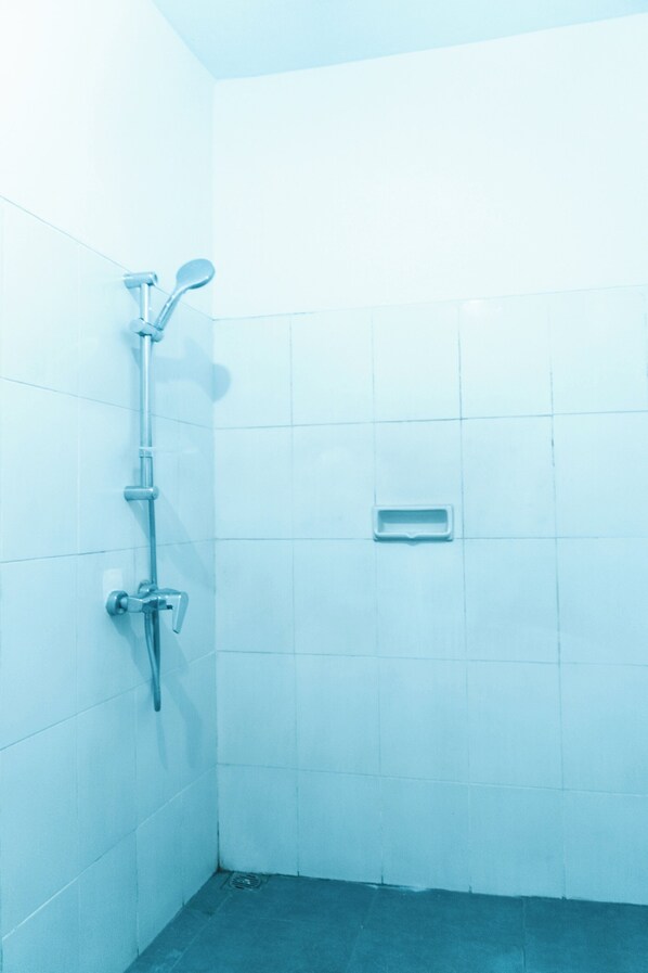 A small, tiled bathroom with a shower, a hand dryer, and a waste bin.