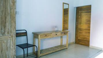 A room with a wooden desk, a chair, a mirror, and a wooden door.