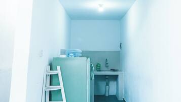 A narrow hallway with a small kitchenette area, a ladder, and a water dispenser.