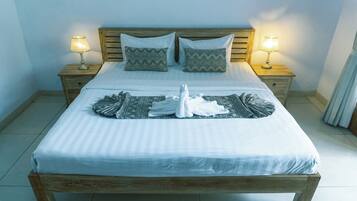 A neatly made bed with two pillows, two bedside lamps, and a folded towel on the bed.