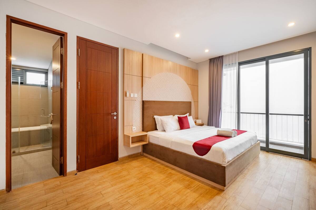 Un dormitorio moderno con una cama grande, un armario de madera y un ventanal corredero a un balcón.