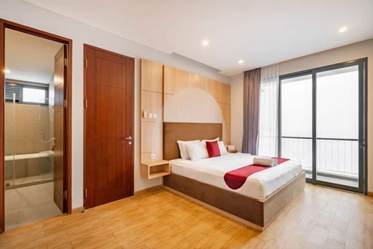 Habitación de hotel moderna con una cama grande, armario empotrado, zona de ducha y balcón con vistas.