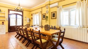 Un comedor con mesa y sillas de madera, paredes amarillas y una araña.