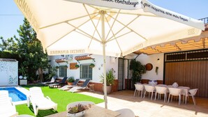 Un patio con piscina, sillas de descanso y una mesa con sillas.