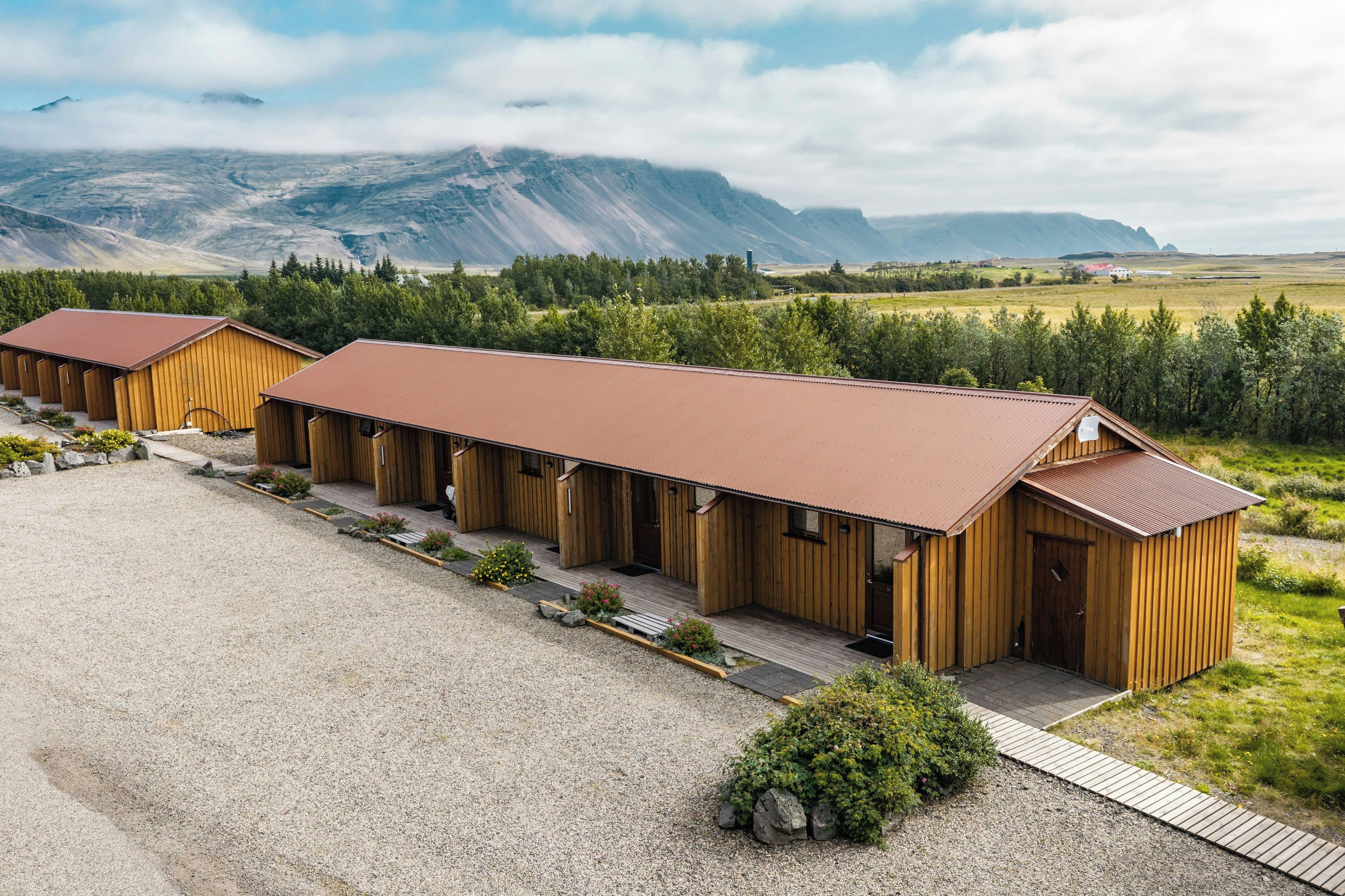 Une rangée de chalets en bois, avec une allée en gravier et une vue sur les montagnes en arrière-plan.
