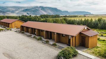 Une rangée de chalets en bois, avec une allée en gravier et une vue sur les montagnes en arrière-plan.