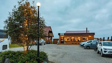 A building with a sign 'ARNANES' and a parking area with cars.