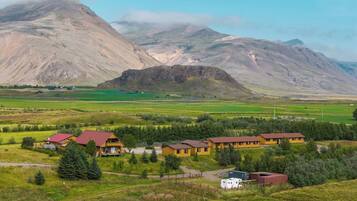 A rural landscape with a row of yellow cabins with red roofs, a white RV, and a small building with a red roof.