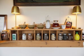 A wooden shelf with various jars, a sugar bowl, a teapot, and a bottle of syrup. - Arnanes Country Hotel (Höfn)