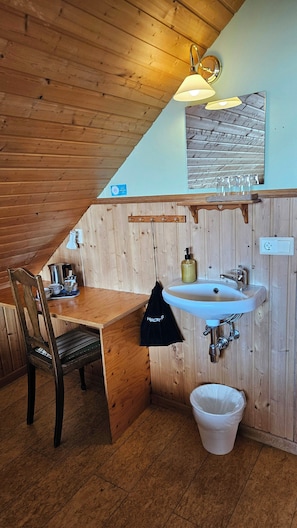 A wooden cabin bathroom with a sink, mirror, and a towel hanging on the wall. - Arnanes Country Hotel (Höfn)