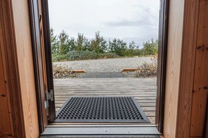 Una terraza de madera que da a un área de grava con una rejilla de metal.