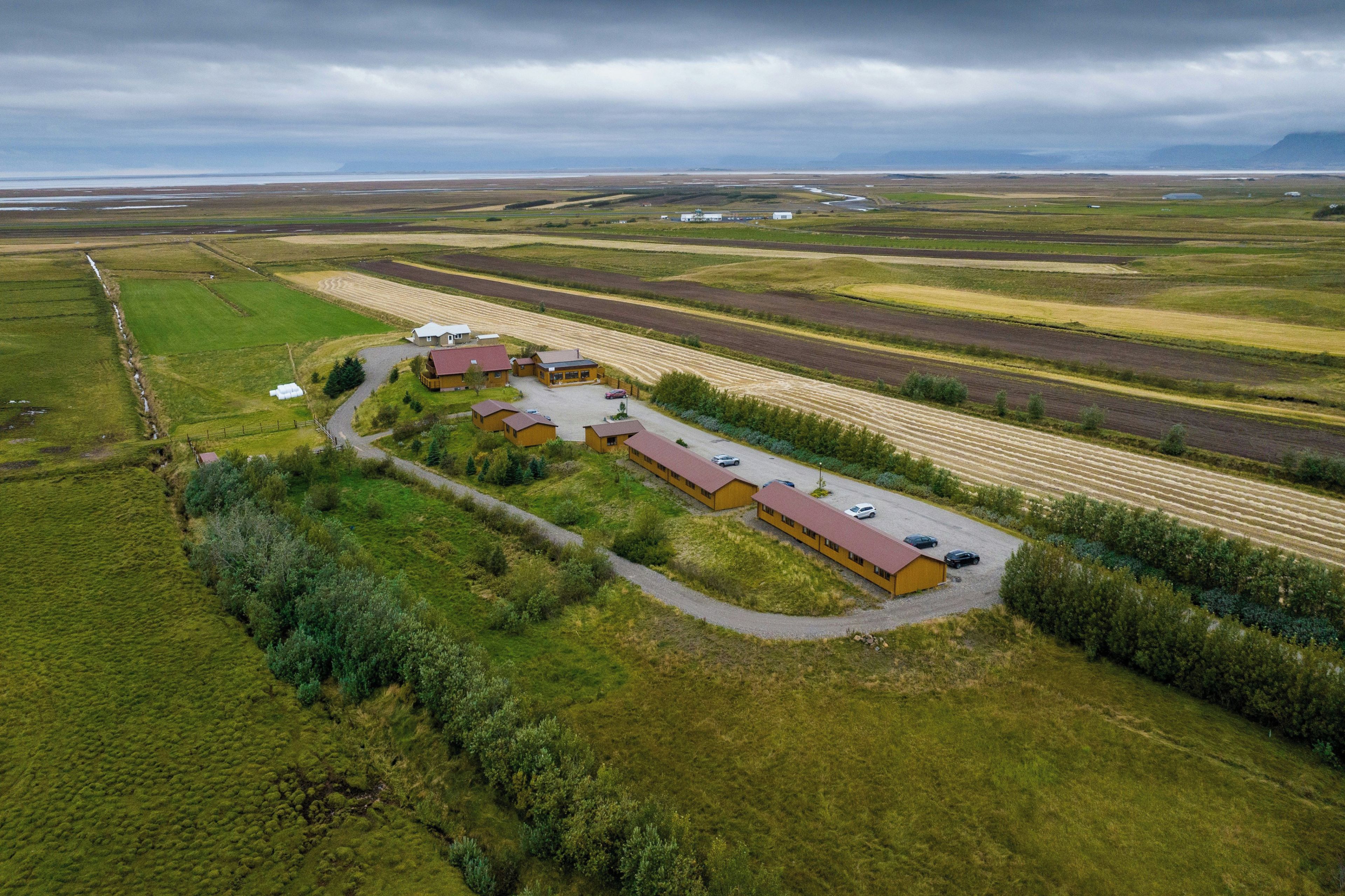 Luchtbeeld van een landgoed met meerdere gebouwen, een grindpad en uitgestrekte velden.