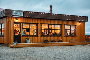 A wooden building with a sign reading 'ARNANES COUNTRY HOTEL' and a reception area visible through the windows. - Arnanes Country Hotel (Höfn)
