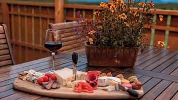 A wooden table with a charcuterie board, a glass of red wine, and a potted plant with yellow flowers.