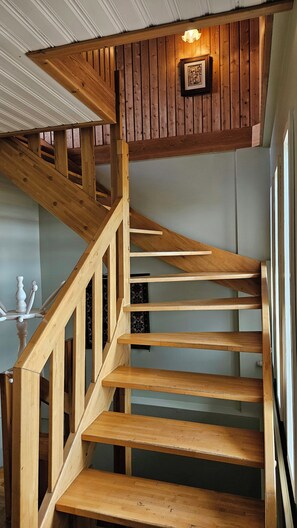 A wooden staircase with a handrail and a light fixture above it. - Arnanes Country Hotel (Höfn)