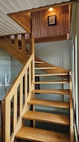 Una escalera de madera con barandilla y una lámpara colgante.