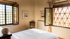 A bedroom with a bed, a chair, a window with a view, and a radiator.
