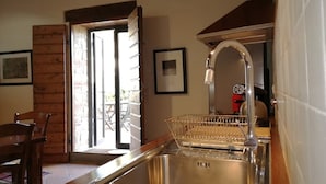 A kitchen with a stainless steel sink, a wooden chair, and a door leading to an outdoor area.