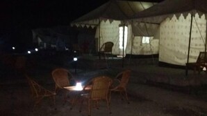 Un terrain de camping avec des tentes et une table entourée de chaises.
