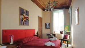 Une chambre à coucher avec un grand lit, une tête de lit en bois, un lustre et des œuvres d’art accrochées aux murs.