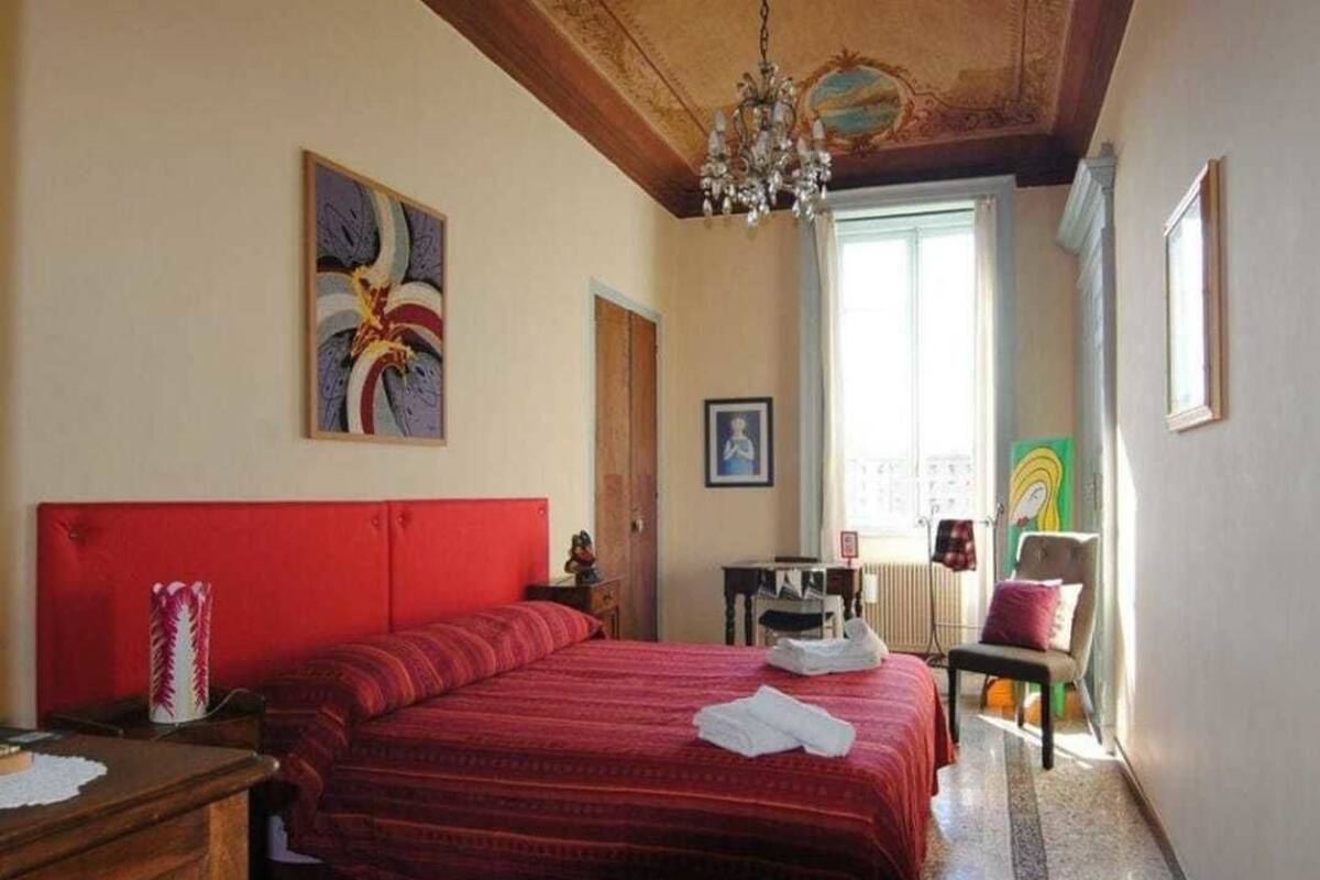 A bedroom with a large bed, a wooden headboard, a chandelier, and artwork on the walls.